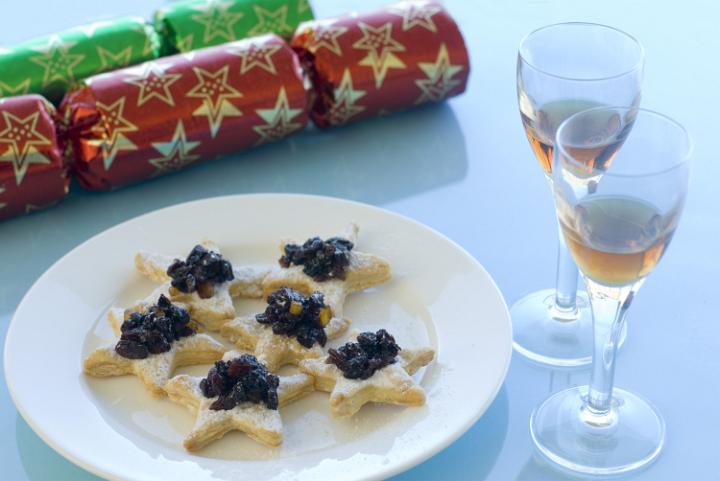 a plate of christmas snack appetisers, sweetcrust pastry and mincemeat with glasses of sherry