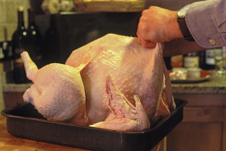 an uncooked turkey plucked and sat in a roasting tray being prepared for stuffing