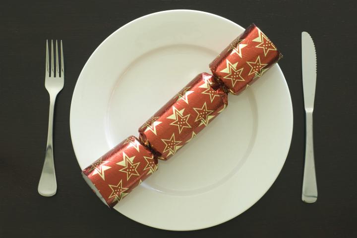 a place setting at a christmas dinner table, plate and christmas cracker
