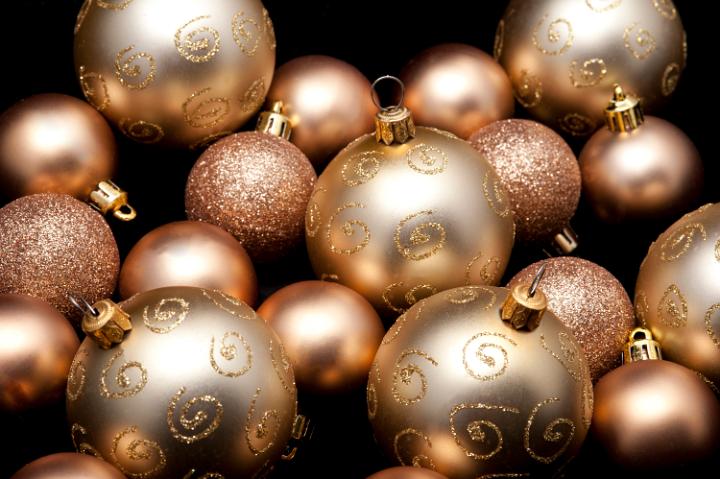 a selection of gold coloured christmas baubles of various sizes on a back background