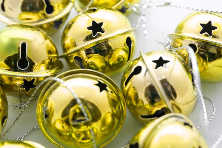 Closeup of shiny gold metallic round Christmas jingle bell ornaments with ties to hang on your Christmas tree for seasonal celebrations