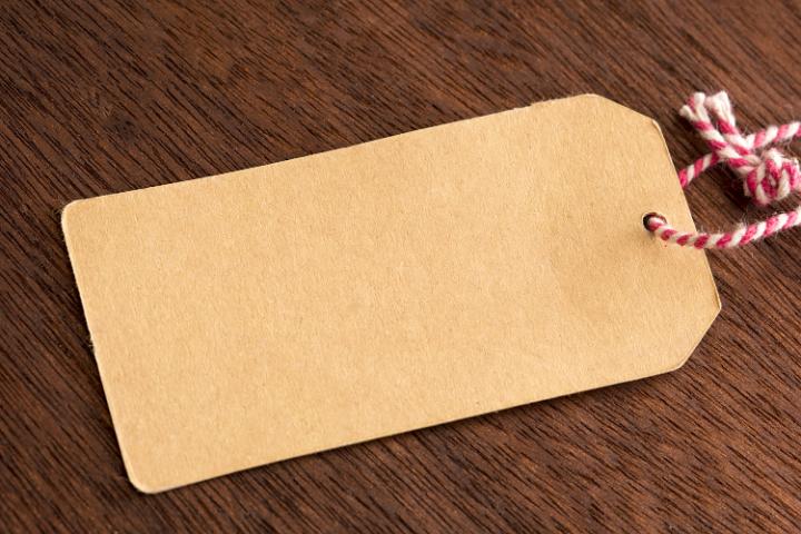 Blank plain brown gift tag or label tied with colorful,red and white string on a wooden table with copy space for your message