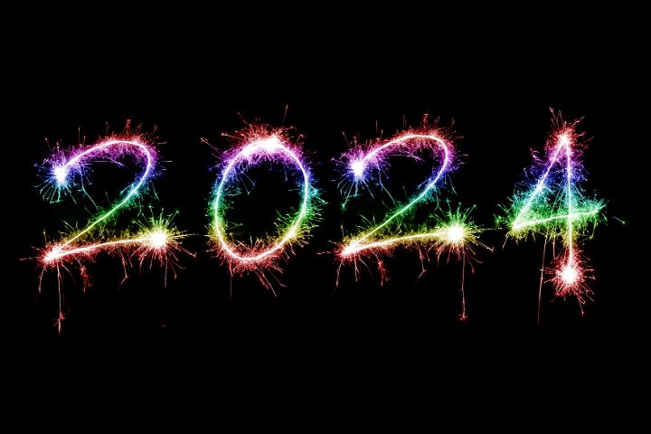 rainbow coloured sparkling fireworks as happy new year holiday 2024 over black background