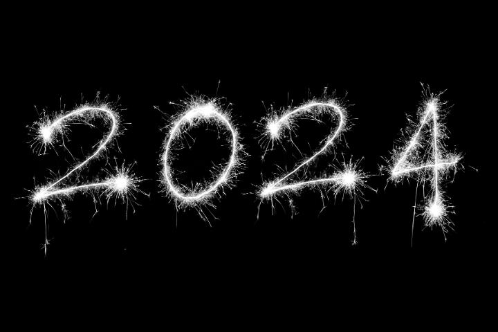 New Years 2024 digits drawn with bright sparkling lights isolated on black background