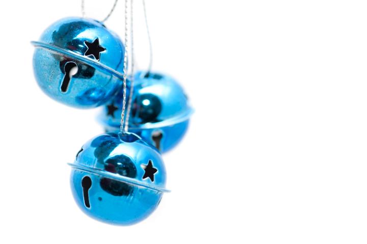 Round metallic blue Christmas bells suspended against an isolated white background with copyspace