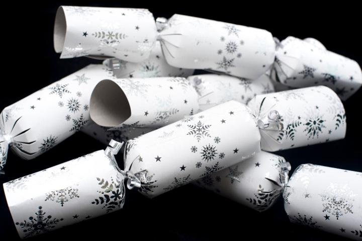 Collection of decorative white Christmas crackers with snowflakes filled with surprises for celebrating the festive season on a black background