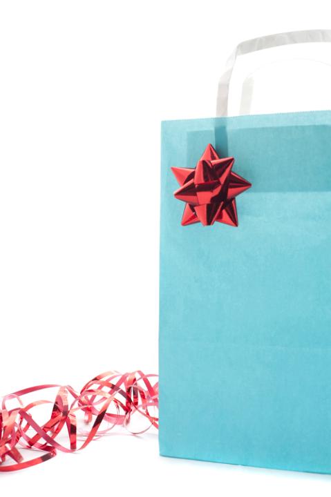Decorated blue gift bag with an ornamental red bow and ribbon to celebrate a special occasion with a loved one isolated on white, close up view