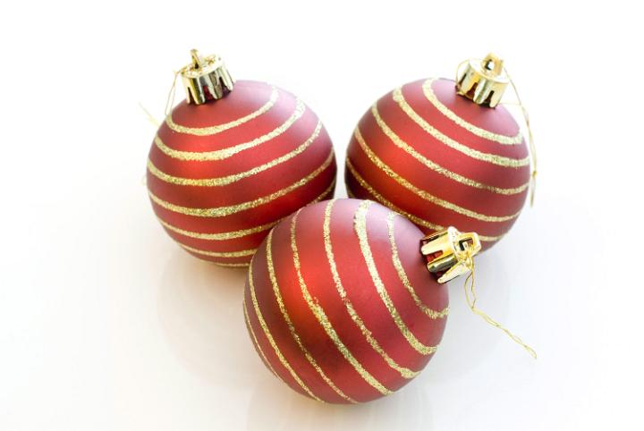 a trio of red christmas tree decorations with gold glitter stripes on a white background