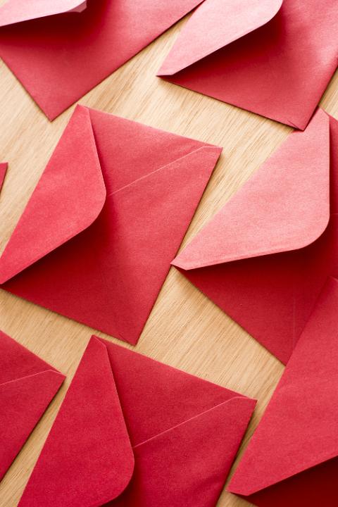 Festive red Christmas or Valentines envelopes lying face down on a wooden table with open flaps in a full frame background