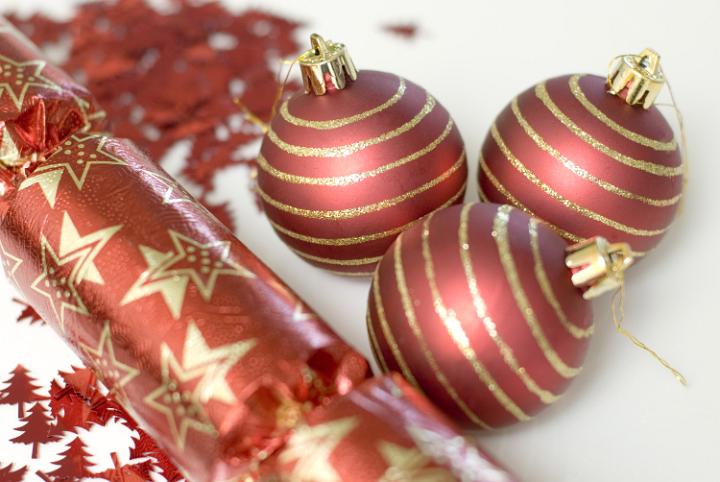 A christmas background composed of three baubles, christmas glitter and a red christmas cracker.