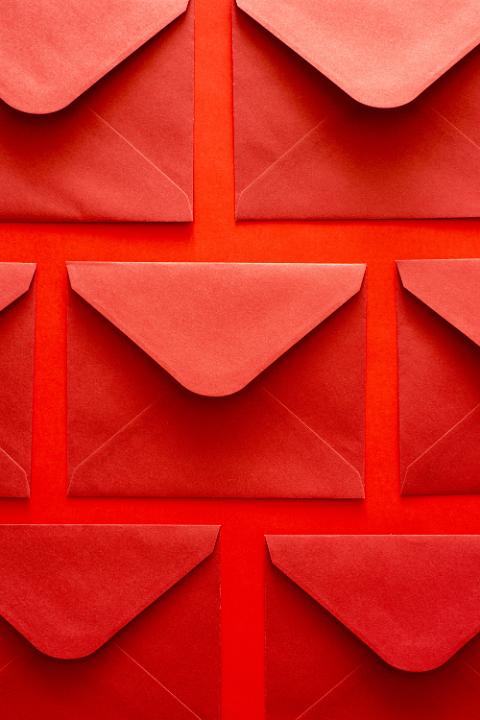 Bright red arrangement of lucky festive envelopes in neat rows as a Christmas or holiday background viewed face down with unstuck flaps