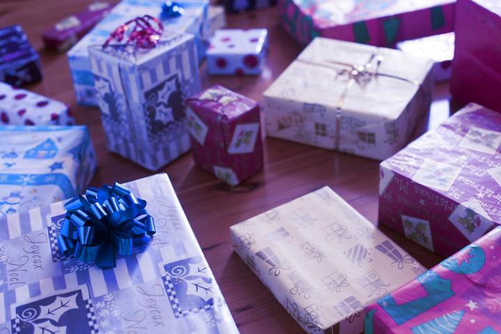 Purple toned background of a large selection of colorful Christmas gifts lying on a wooden floor