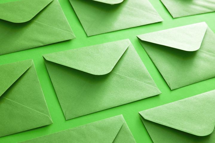 Colorful green envelope background neatly arranged face down with open flaps in diagonal rows in a correspondence and communication concept