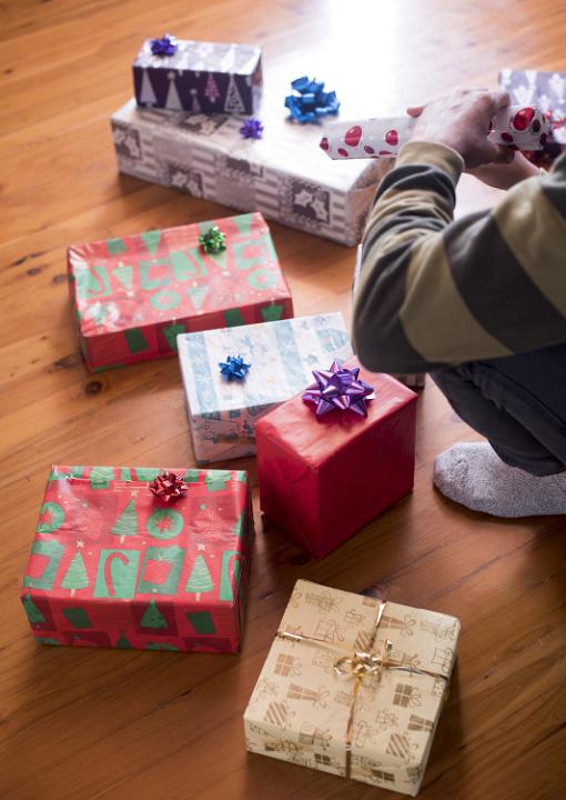 A child opening presents on wooden floor on Christmas morning.