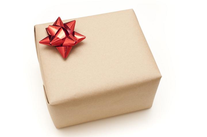 Plain brown paper wrapped gift box decorated with a festive rd bow for Christmas, birthday, anniversary or Valentines, high angle over a white background