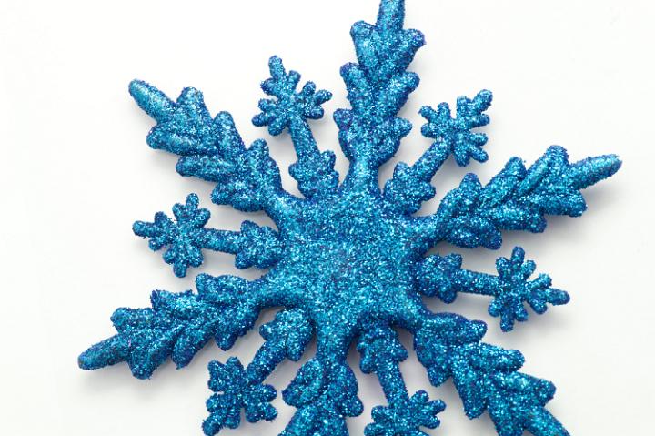 Decorative blue Christmas snowflake ornament with a textured shiny surface on a white background