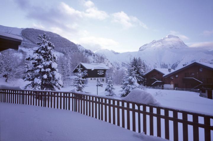 a winter scene, early morning in the french alps, a small apline town covered in snow