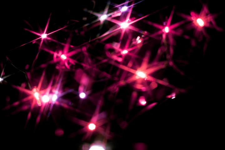 Christmas background of colourful vivid pink starburst lights scattered in the darkness sparkling and glowing for a fesive greeting card or seasonal wishes
