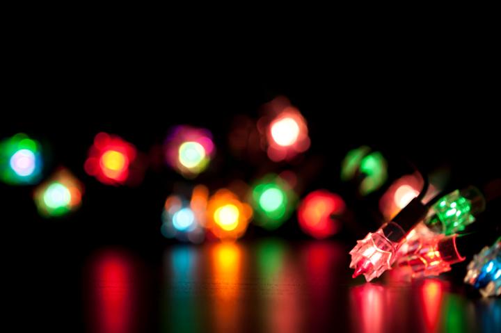 Colourful Christmas lights with selectove focus, blur and reflections on a dark background with copyspace for your seasonal greetings